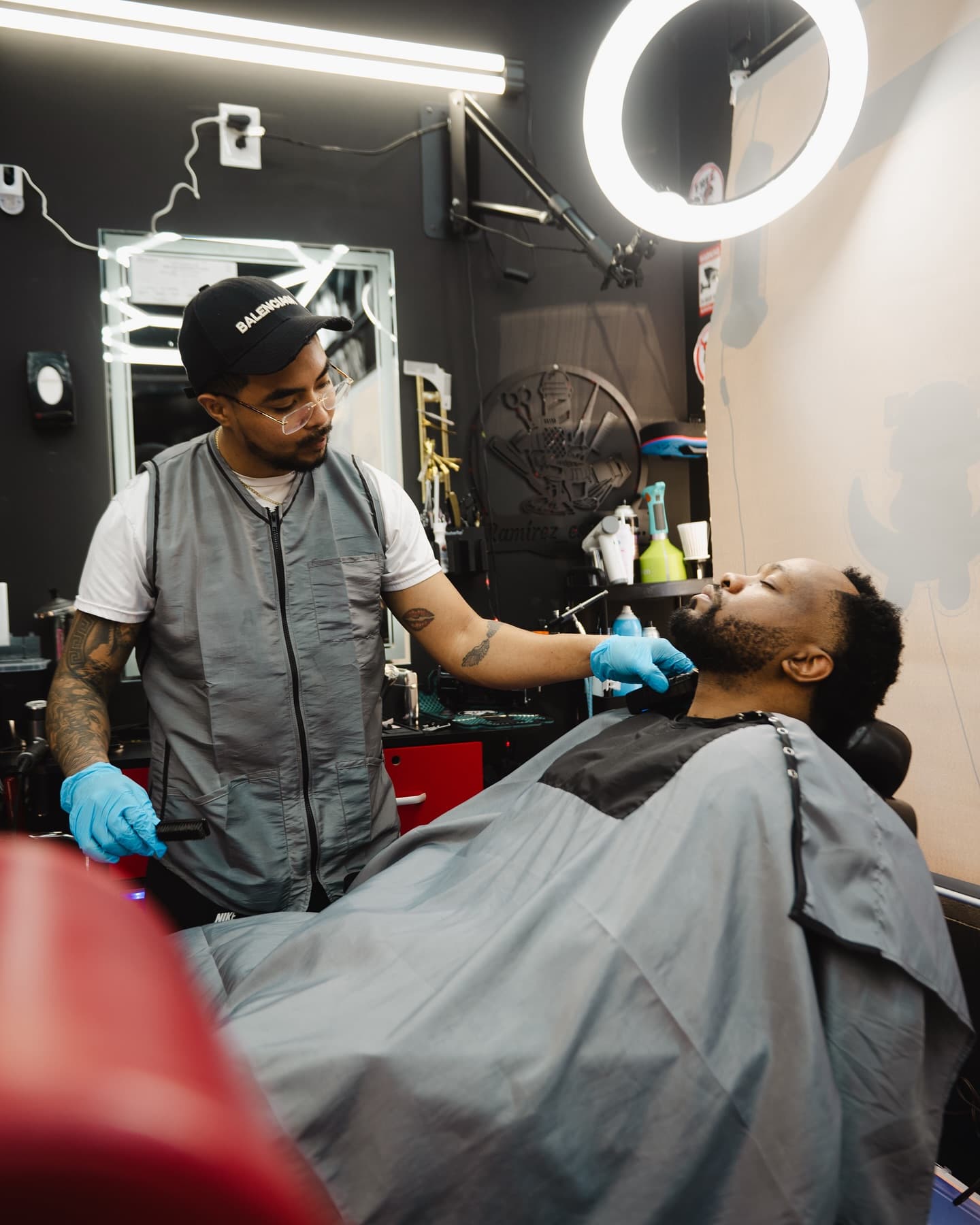Barber shaping a client's beard inside their own branded private barber suite near Baltimore